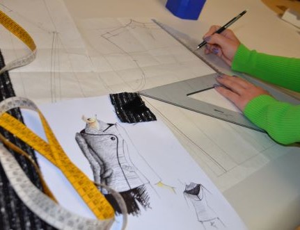 cartamodello Modellista al lavoro su cartamodelli industriali. Immagine ambientata che rappresenta l’accuratezza della fase di progettazione tecnica nel settore moda.