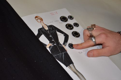 bozzetto Figurino di moda accostato ad un tessuto e a dei bottoni
