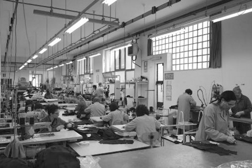 Laboratorio di confezione Interno di un laboratorio di confezione moda con operatori al lavoro su macchine da cucire industriali e postazioni di assemblaggio.